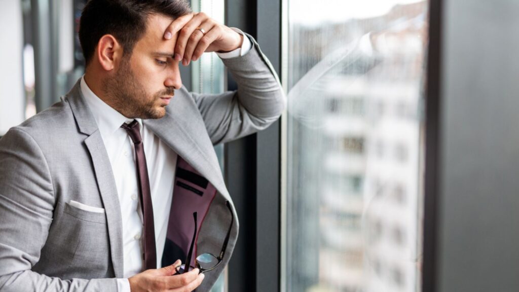Portrait of frustrated stressed sad young business man working in corporate office
