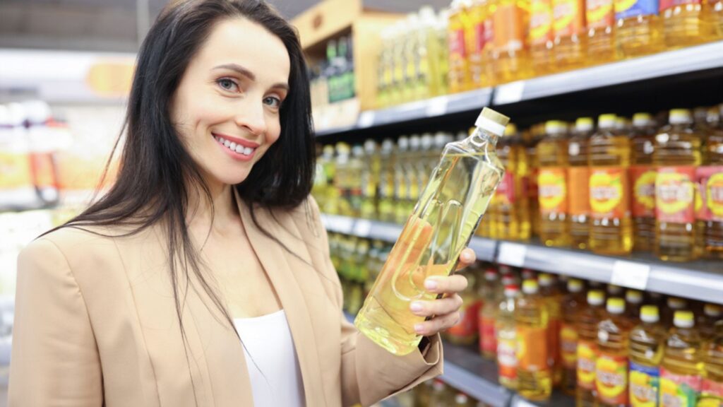 Portrait of smiling woman holding sunflower oil in shop. Choosing the right cooking oil concept