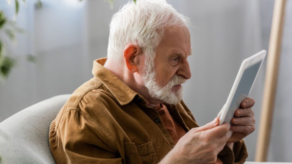 Selective focus of angry senior man using digital tablet