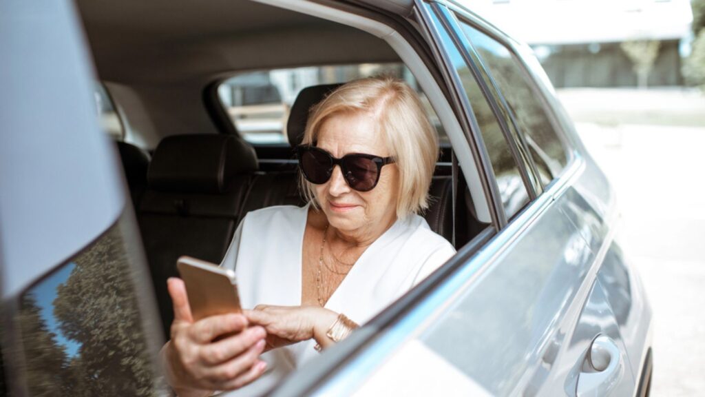 Senior woman with phone in the car