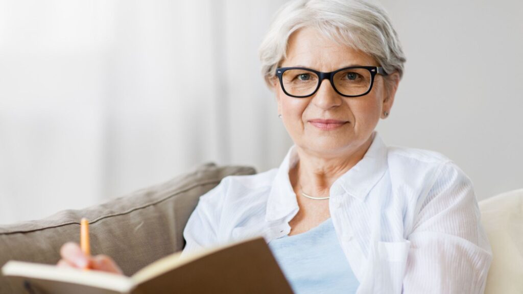Senior woman writing to notebook or diary at home