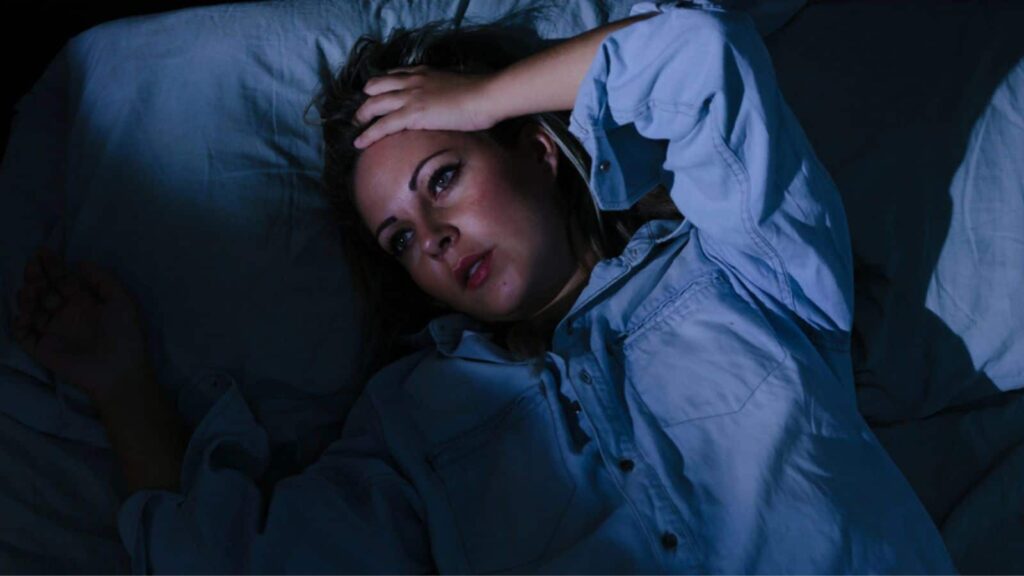 Sleep disorder, insomnia. Young blonde woman lying on the bed awake