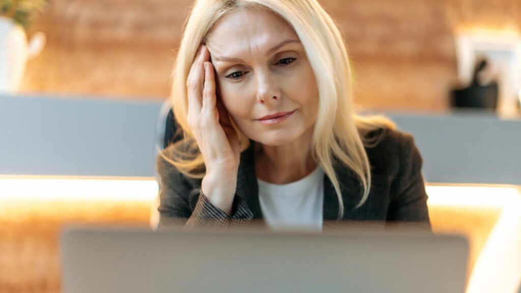 Stress sad tired old woman working on her laptop