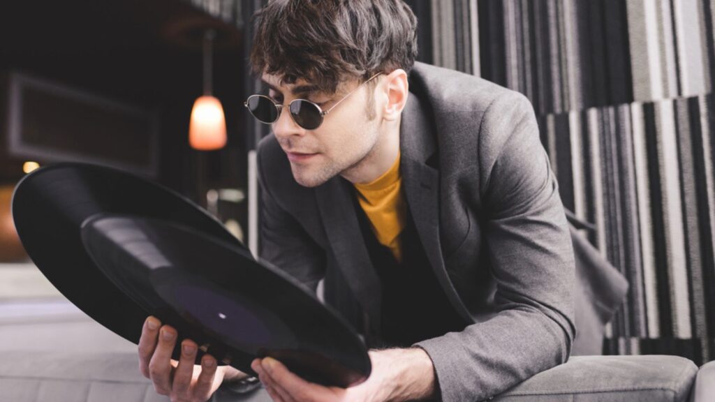 Stylish young man in sunglasses looking at retro vinyl records