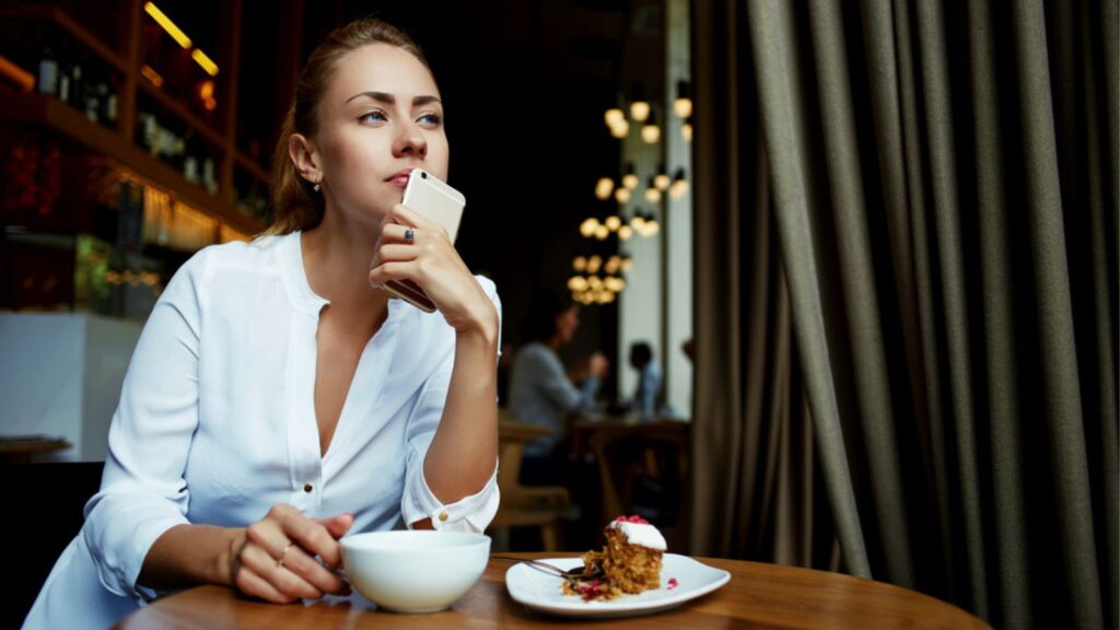 Thinking woman at the restaurant holding a phone