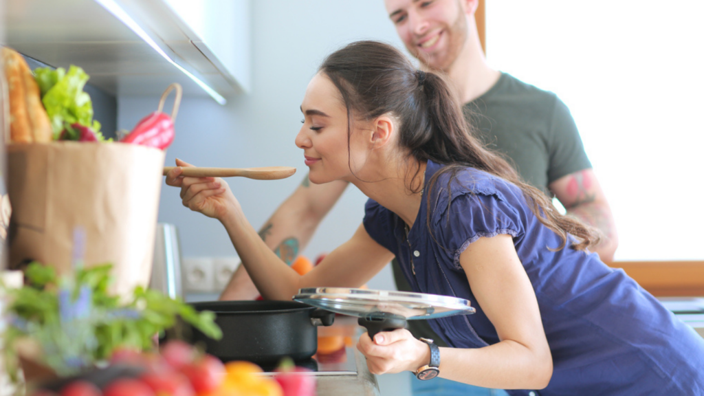 Young woman smelling the tasty pasta in kitchen