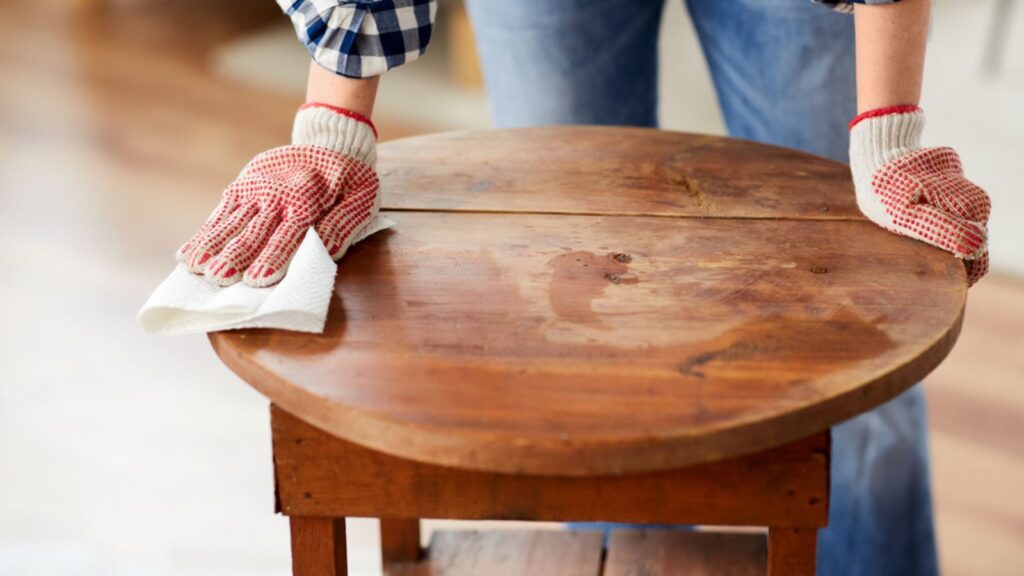 Woman cleaning old table surface