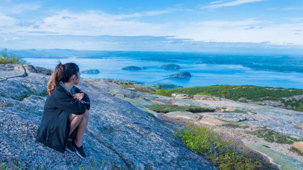 Woman enjoying the beautiful view of small islands seen from Cadillac mountain in Acadia National Park Maine USA