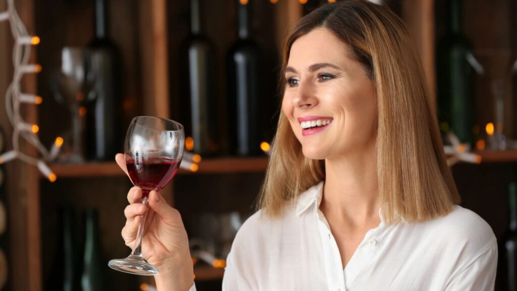 Woman with a glass of wine dreamy looks Happy girl drinking wine