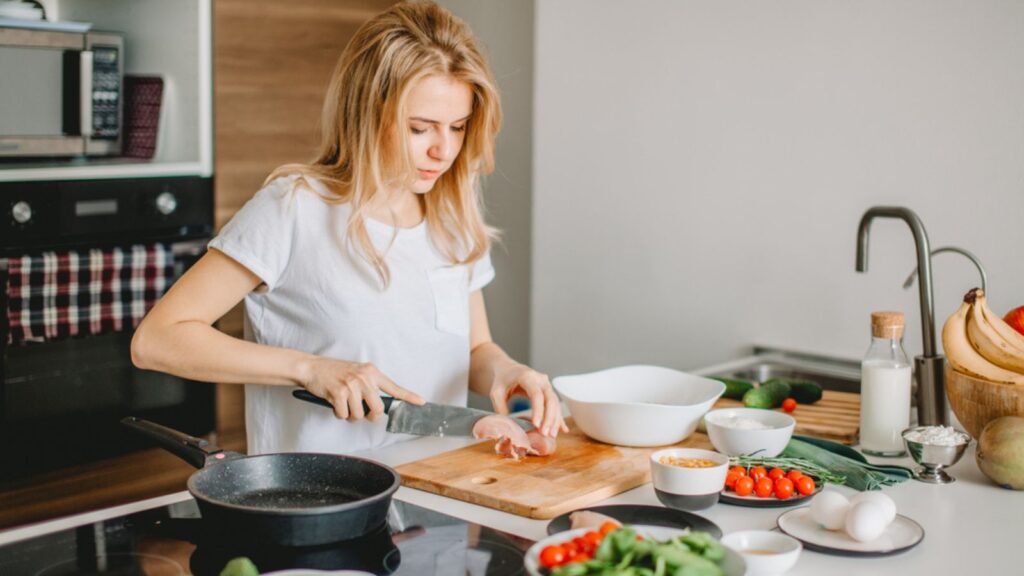 Young hardworking housewife cooking for husband at home