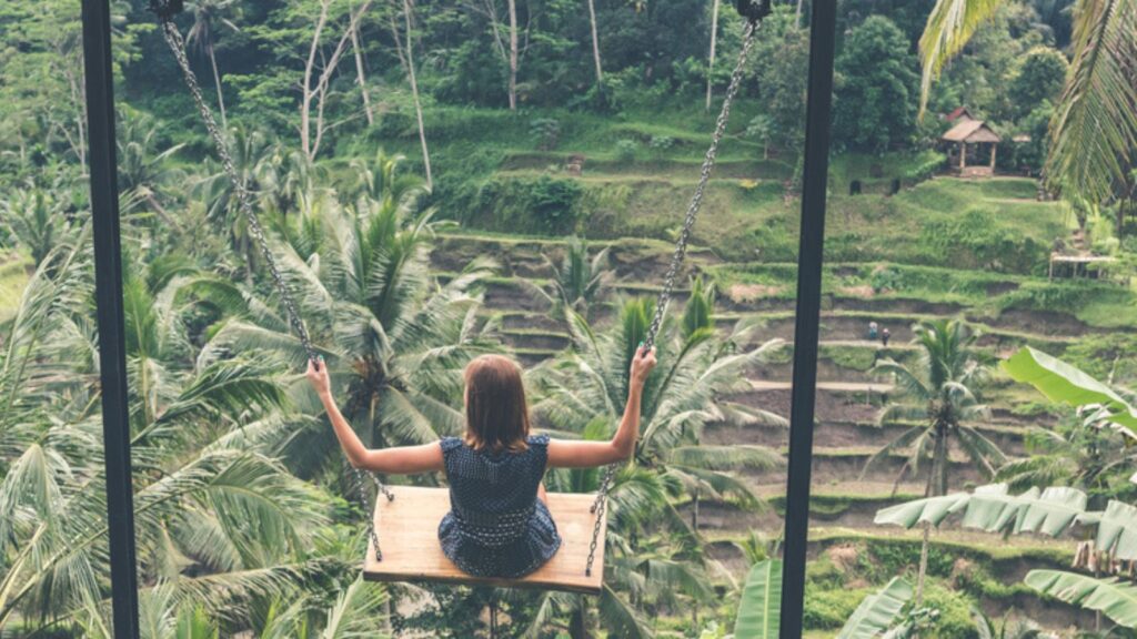 Young woman swinging in the jungle rainforest of Bali island, Indonesia