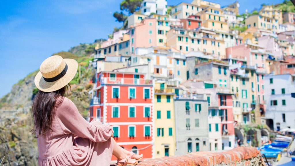 Young woman with great view at old village Riomaggiore, Cinque Terre, Liguria, Italy. European italian vacation