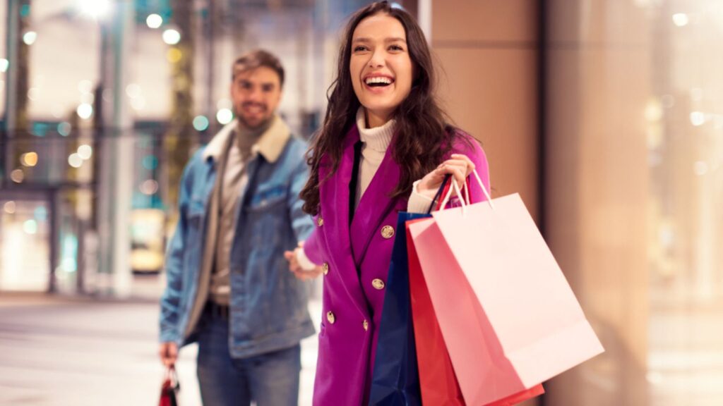 happy couple walking near modern mall outdoor holding hands and shopping bags