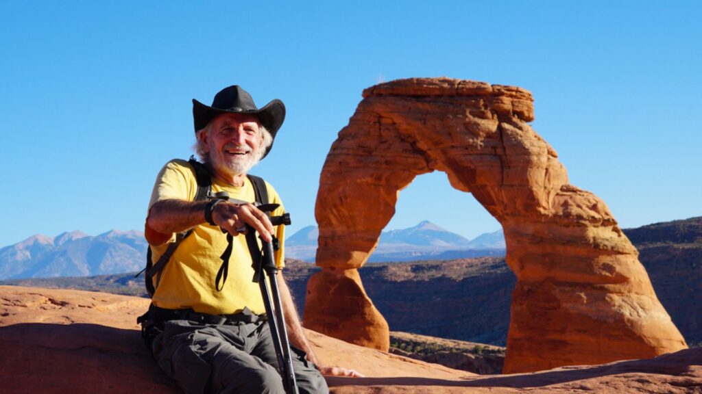 happy old man hiker traveler sitting on rock in arches national park moab utah