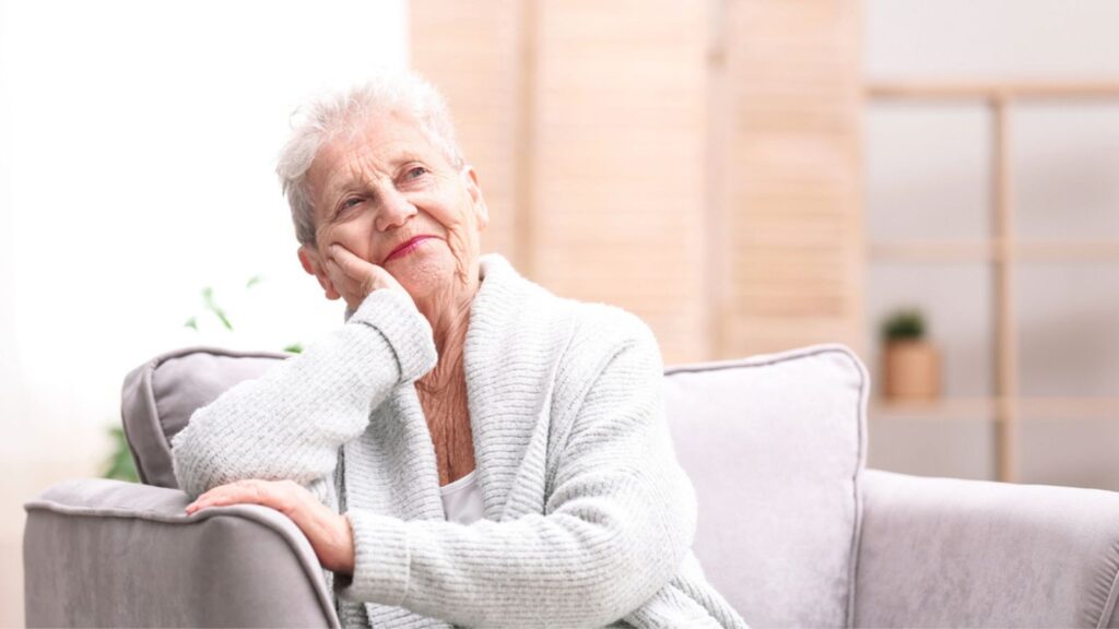 happy peaceful content relaxed old elderly retired woman sitting on couch smiling