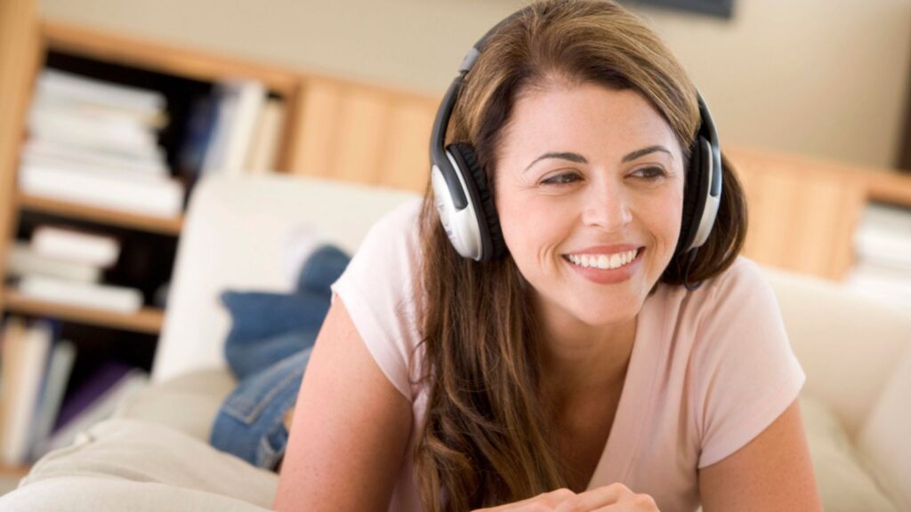 happy woman laying in bed with headphones