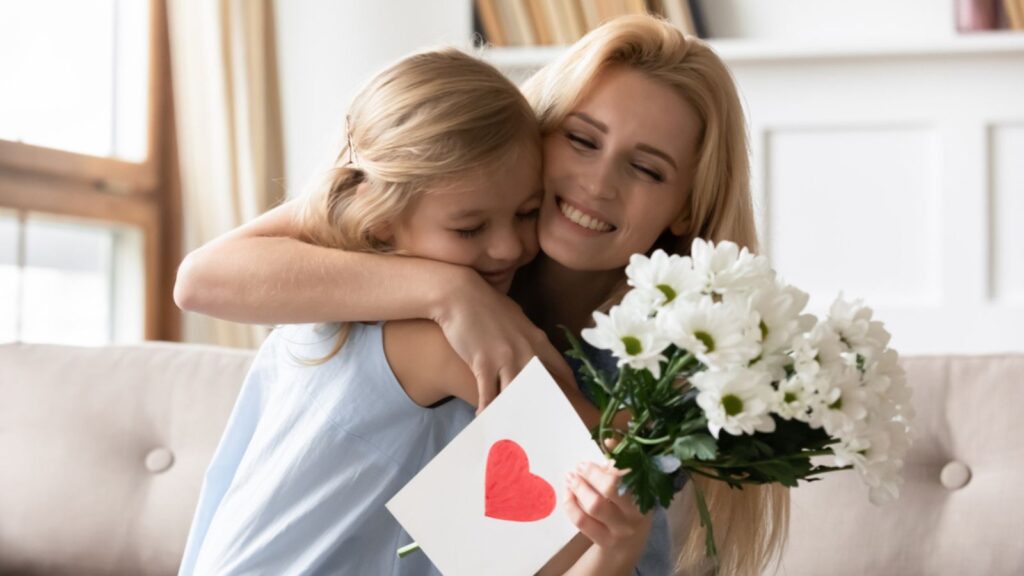mother hugging small child daughter with gift of flowers and valentines day car grateful