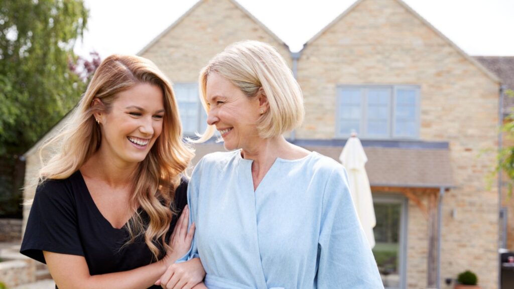 old mother and adult daughter at home laughing walking talking