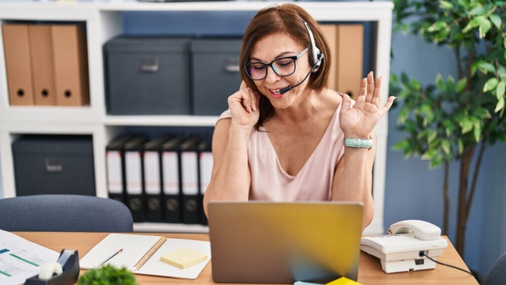 red-haired woman with headset on talking working smiling on laptop