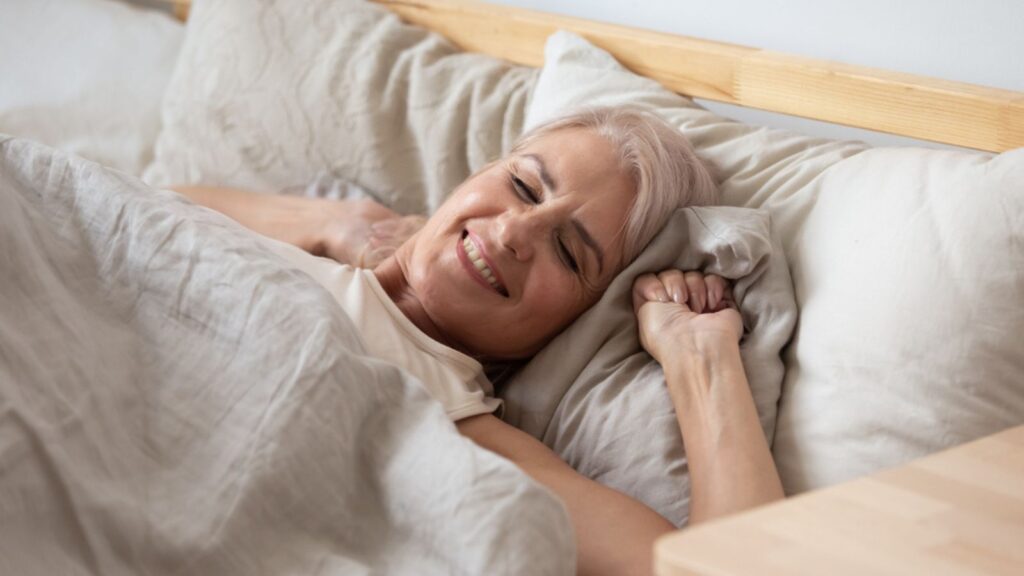 smiling happy retired old woman morning waking up in bed