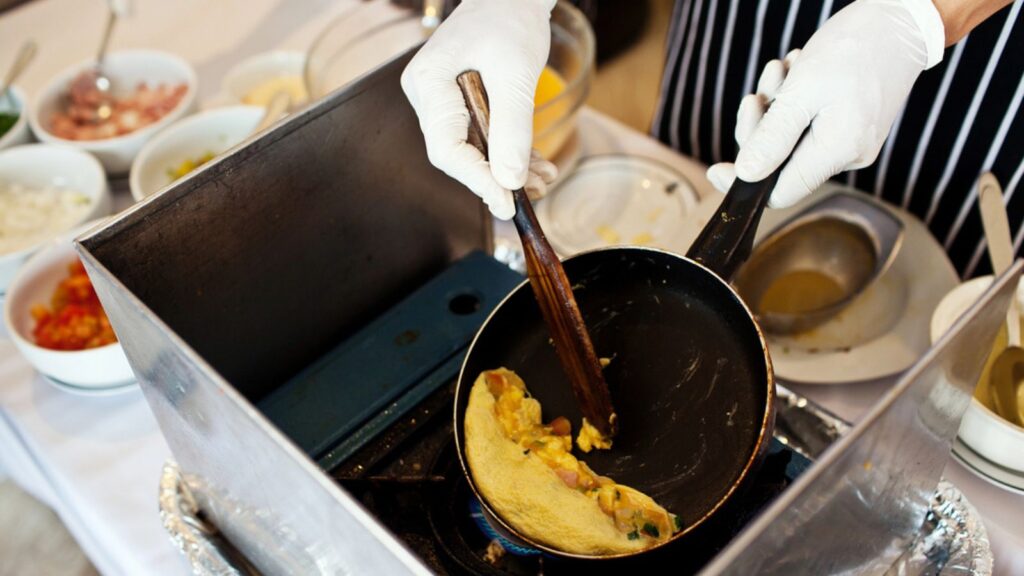 A chef is cooking omelette at restaurant kitchen