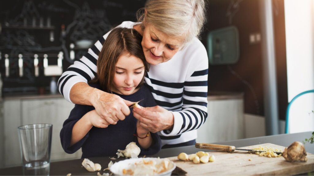 A small girl with grandmother cooking at home