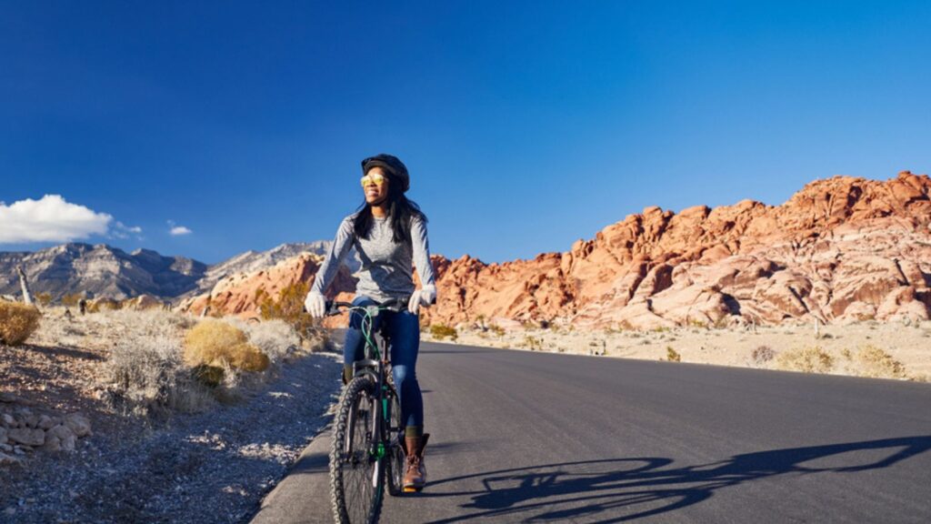 African american woman riding bicycle through red rock canyon park, Nevada