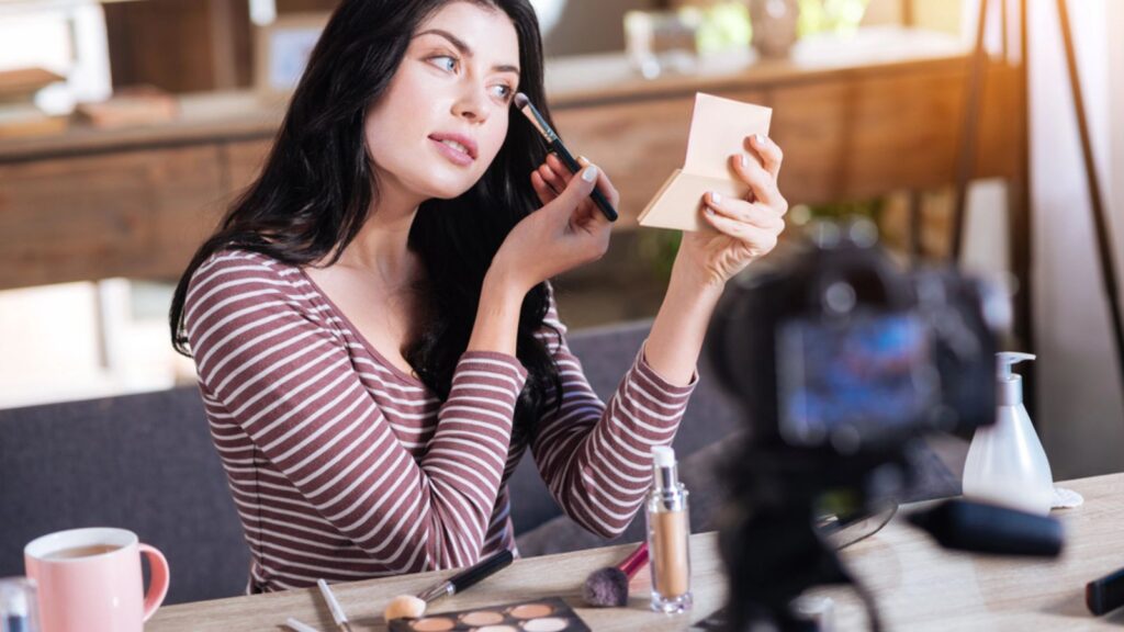 Attractive young woman applying make up to her face