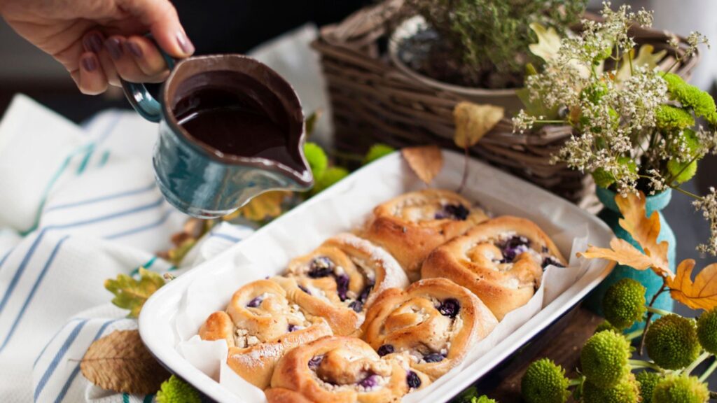 Cinnabon with chocolate. Homemade pastries in baking dish. Delicious family breakfast and hand in the frame. Free space for text. Top view.