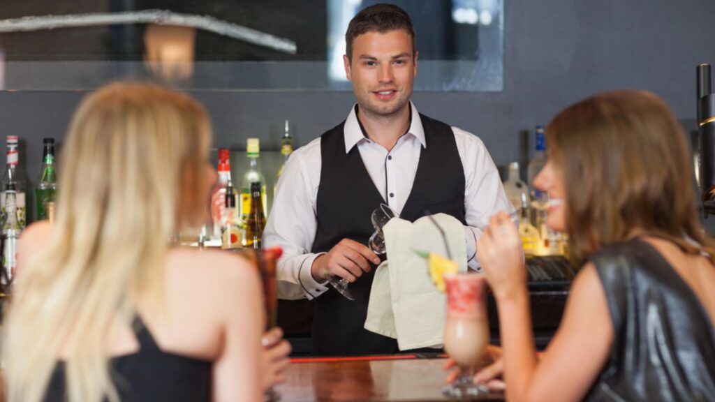 Handsome bartender working while gorgeous women talking