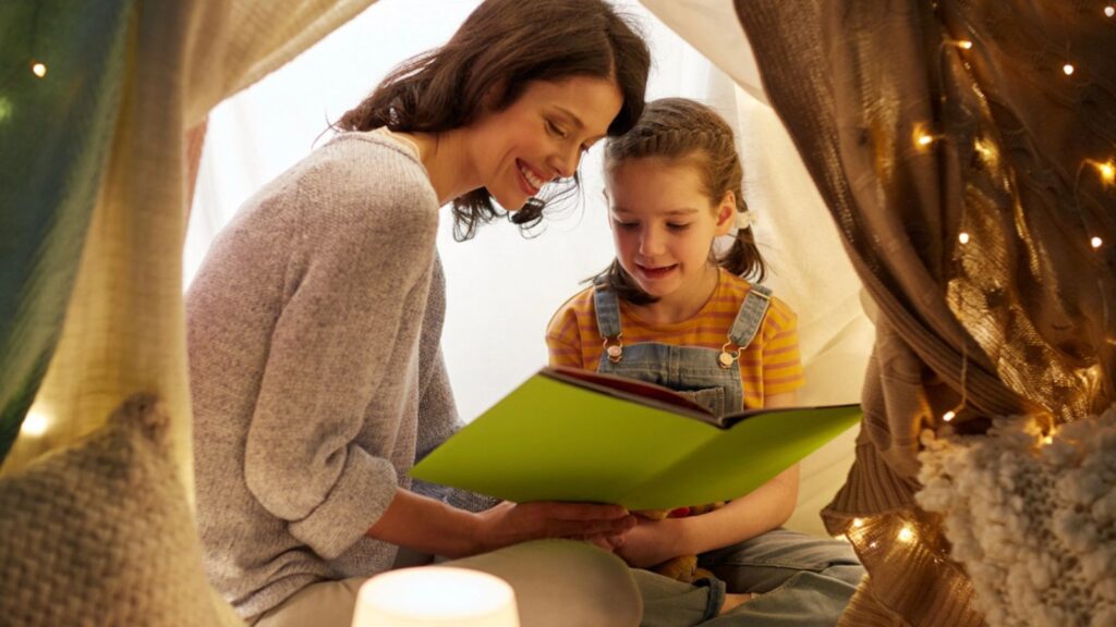 Happy family reading book in kids tent at home