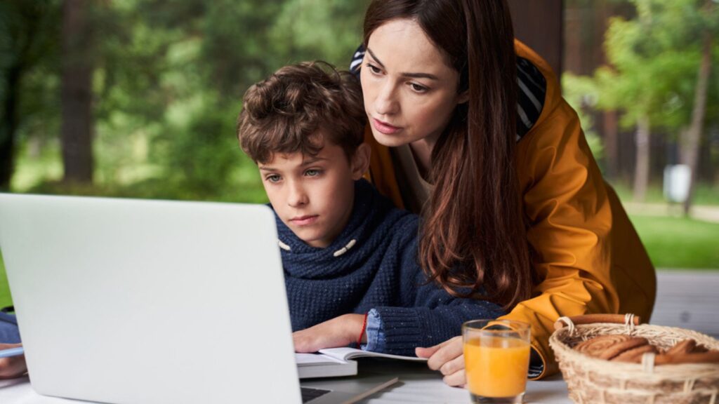 Loving mother helping son to do homework outdoors