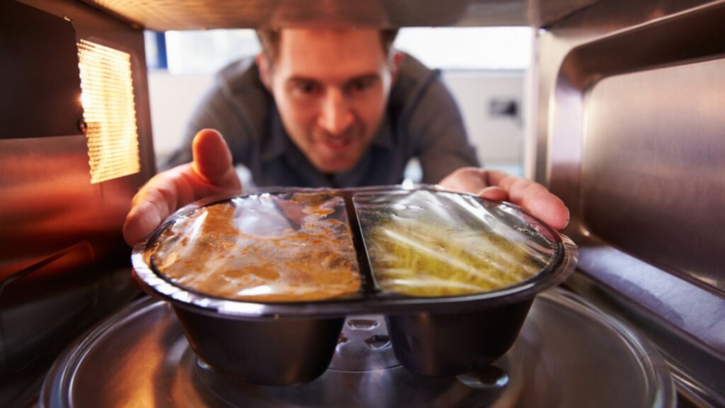 Man Putting TV Dinner Into Microwave