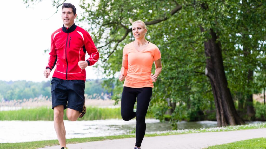 Man and woman jogging together on forest path outdoors