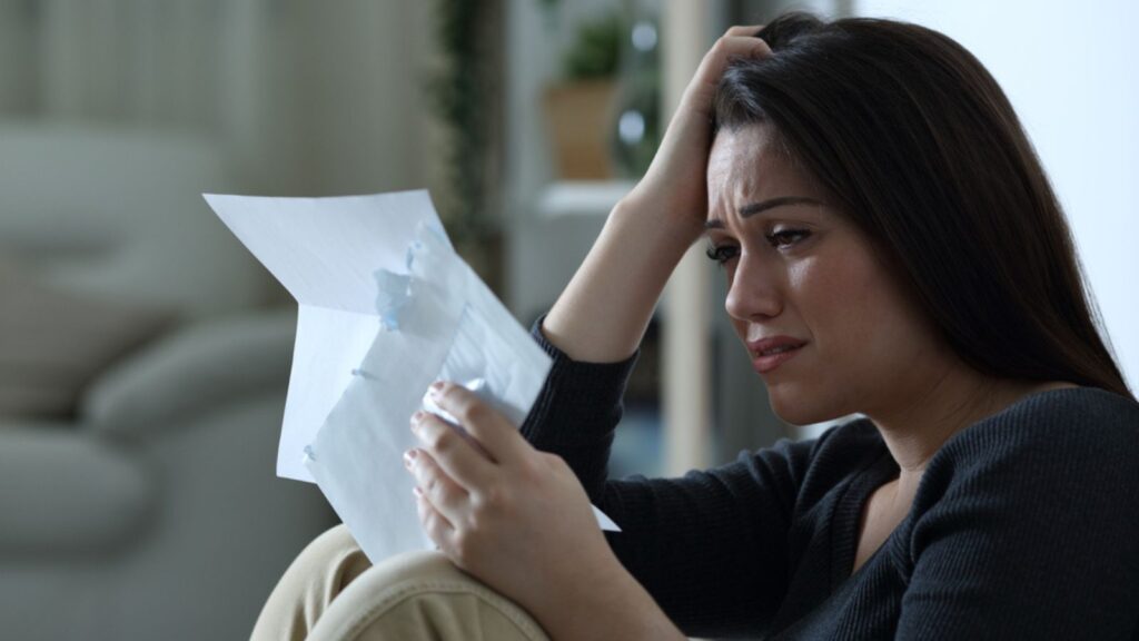 Sad woman reading a letter complaining alone at home in the night