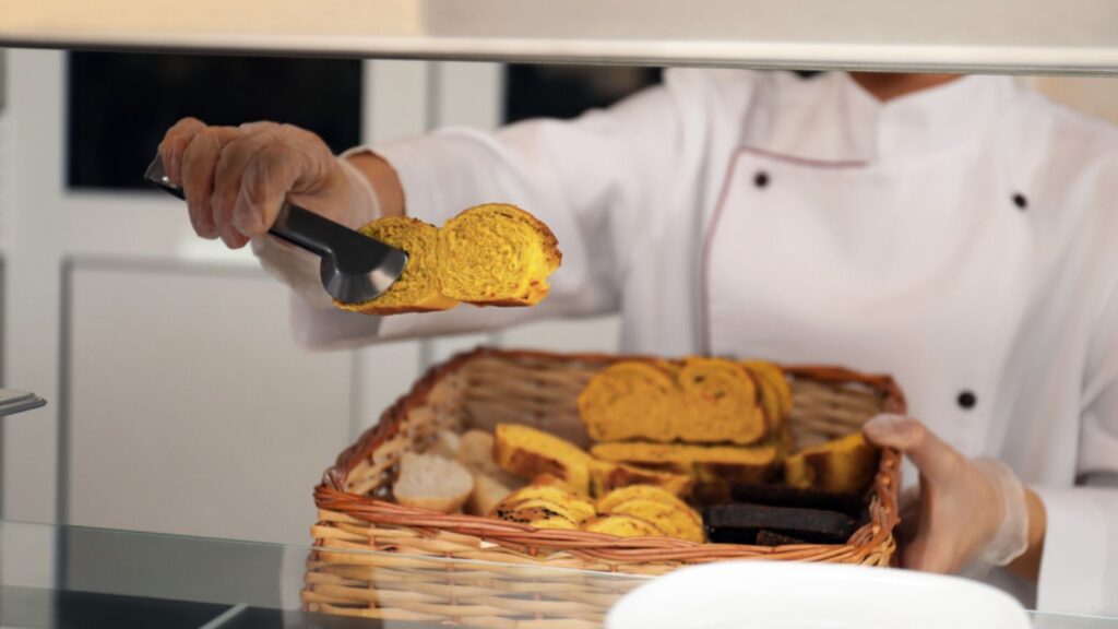 School canteen worker with basket of bread at serving line, closeup