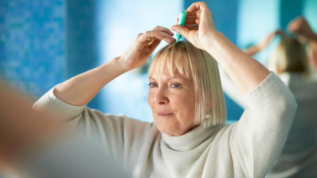 Senior woman checking hairline for hair loss