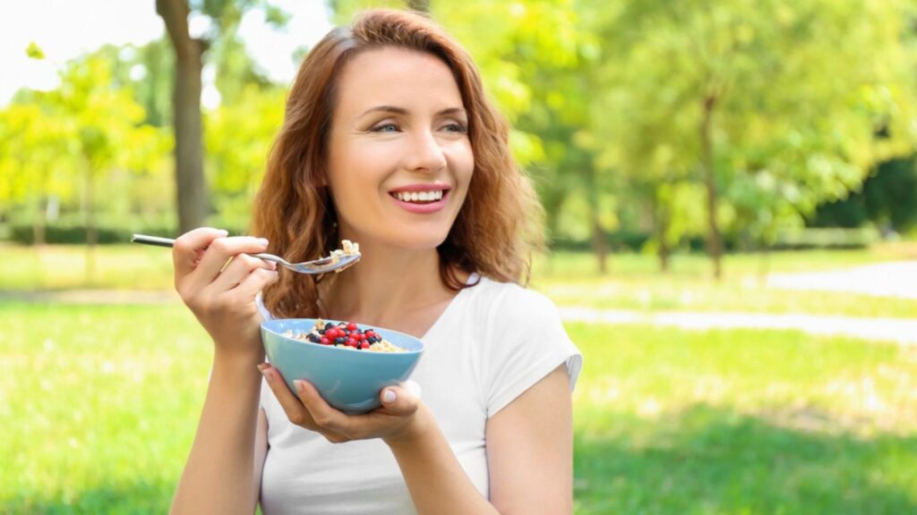 Woman eating tasty oatmeal outdoors