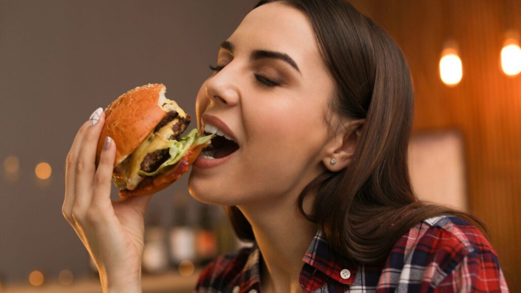 Young woman eating tasty burger