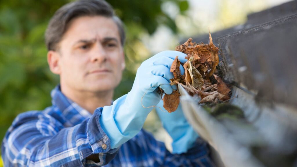 man cleaning gutters house maintenance upkeep