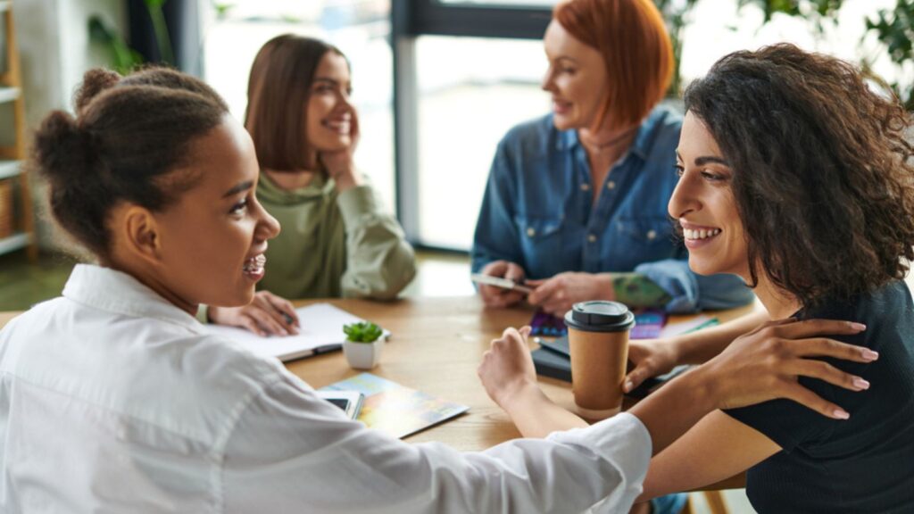 multiracial woman with takeaway drink looking and talking to each other