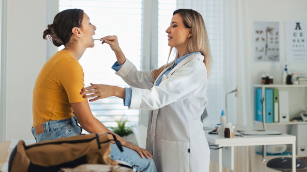 woman doctor looking at patient tongue
