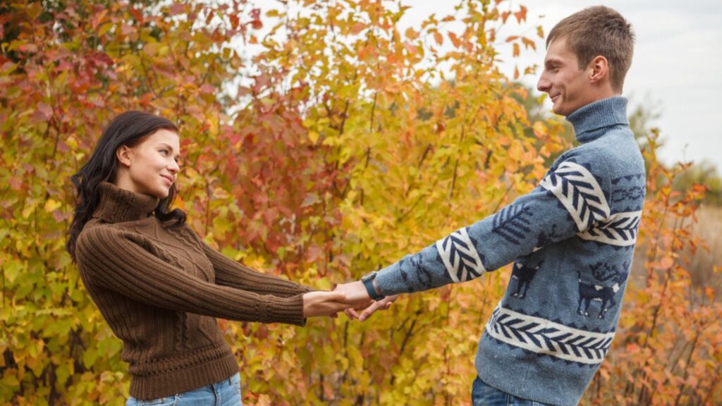 A loving couple holding hands in autumn park outdoors