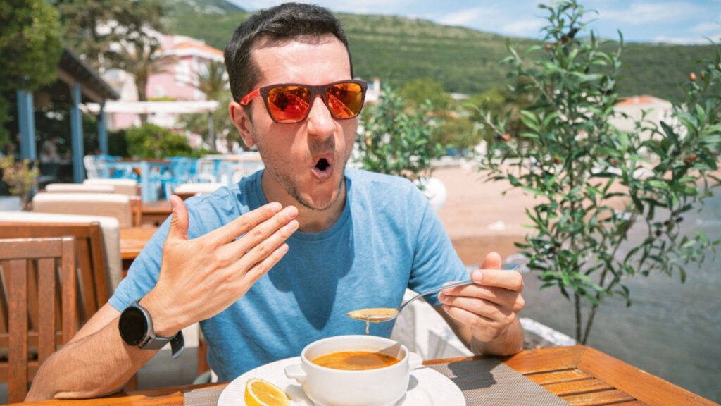 A man holding a bowl of hot and spicy soup, enjoying a satisfying lunch