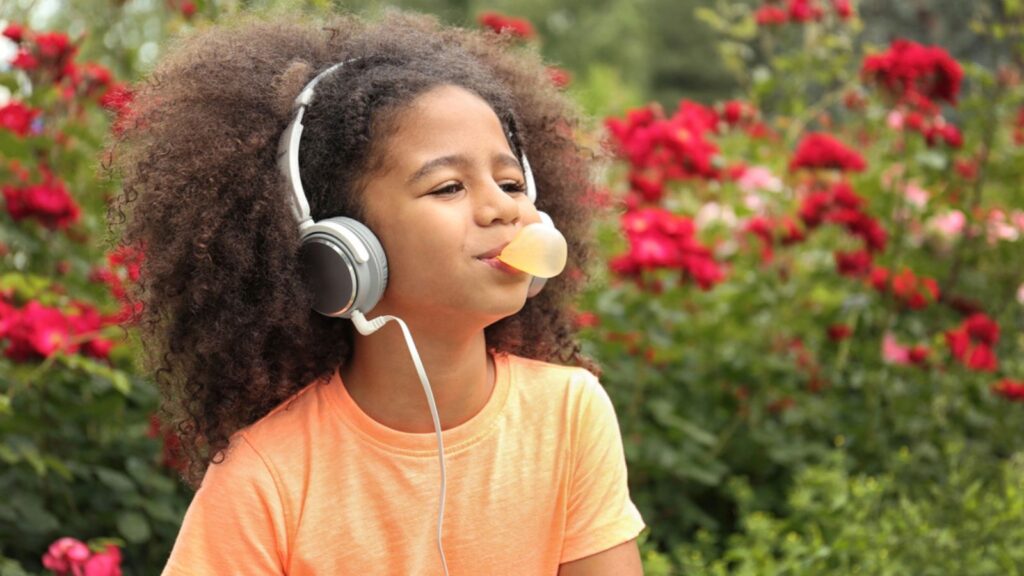 Afro-American little girl with sunglasses playing chewing gum