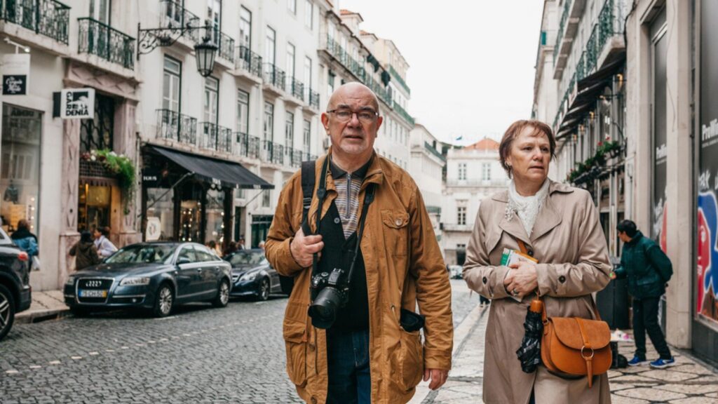 An elderly couple of European tourists are walking around Lisbon in Portugal