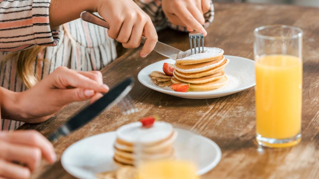 Cropped shot of mother and daughter eating pancakes with strawberries