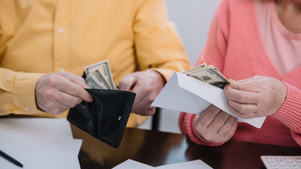 Cropped view of senior couple holding wallet and envelope with money