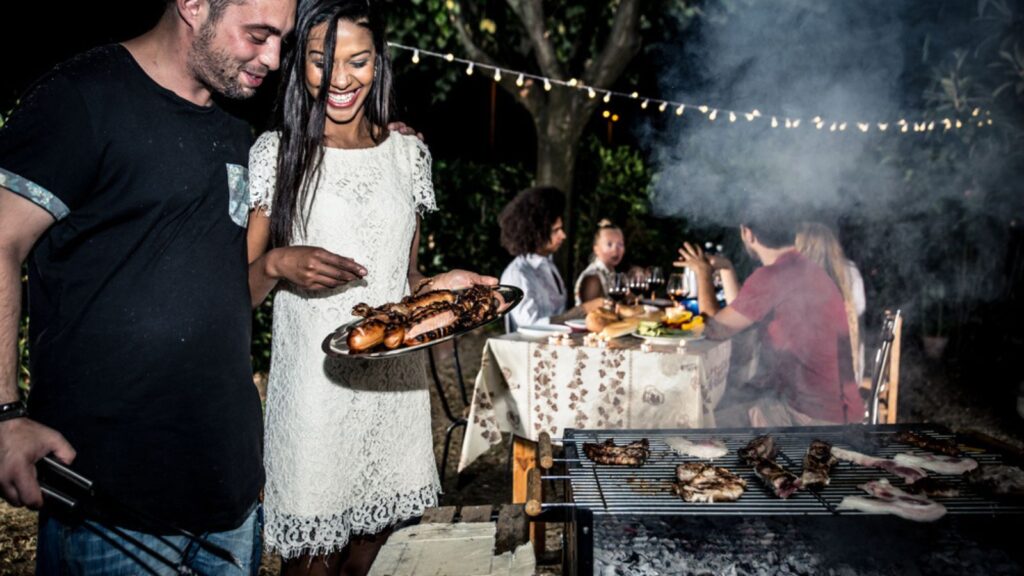 Friends making barbecue in backyard