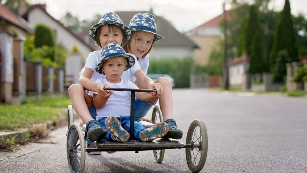Happy children, boys, riding old retro car with four wheels